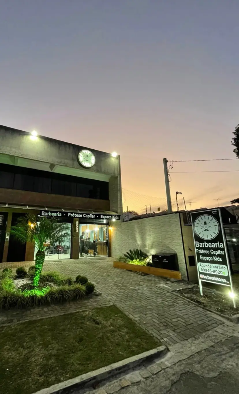 Fachada da Barbearia Barão ao entardecer, com a placa iluminada