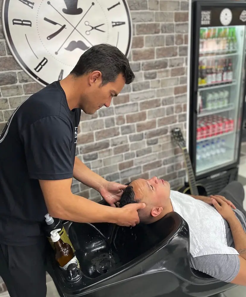 Matuza lavando o cabelo de um cliente no lavatório