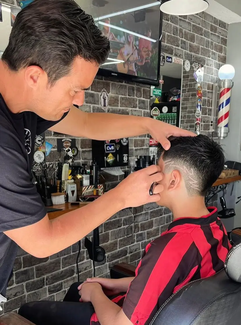 Matuza fazendo um degradê com desenho no corte de um menino