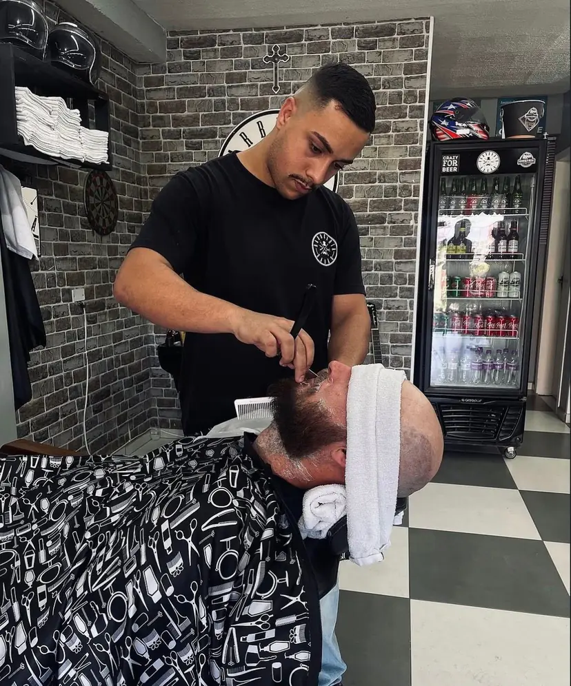 Richard acertando a barba de um cliente na navalha