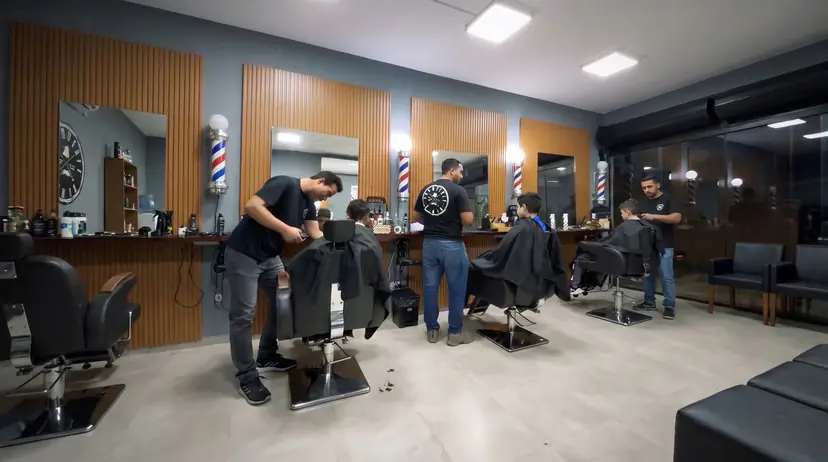 Os três barbeiros atendendo lado a lado no salão da Barbearia Barão